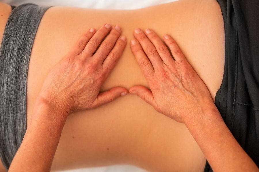 Mains appliquant un drainage sur la zone lombaire, massage anticellulite